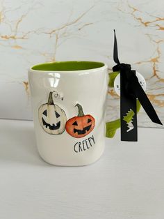 a ceramic mug with two pumpkins on it and a black ribbon tied around the cup