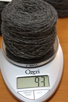 a skein of yarn sitting on top of a scale next to a digital thermometer