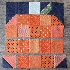 an orange and blue patchwork piece on top of a wooden table