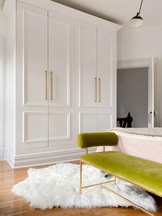 a green bench sitting on top of a hard wood floor next to white cabinets and drawers