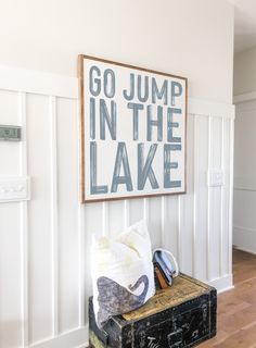 there is a sign that says go jump in the lake next to an old suitcase