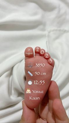 a hand holding a baby's foot with the date and birth numbers on it