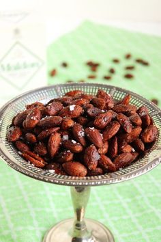 a glass bowl filled with nuts sitting on top of a green and white tablecloth