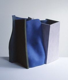 a blue and black vase sitting on top of a white table next to each other