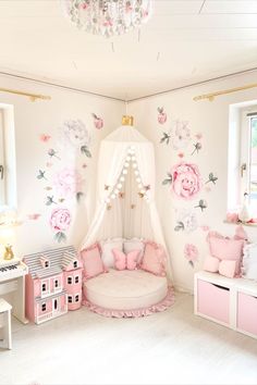 a pink and white bedroom with flowers on the wall, bedding and furniture in it