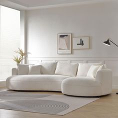 a living room with a large white couch and rugs on the wooden flooring