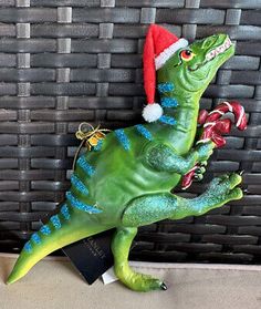 a green toy dinosaur with a santa hat and candy canes