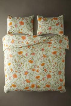 an orange and yellow floral print bedding set with two pillow cases on the side