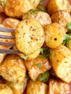 a close up of a fork with some potatoes on it and parsley in the background