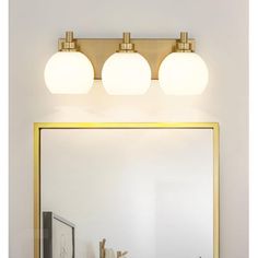 a bathroom vanity with three lights and a mirror on the wall next to it,