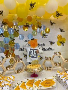 a table with honey themed desserts and balloons