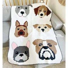 a crocheted blanket with dogs on it in different colors and sizes, sitting next to a couch