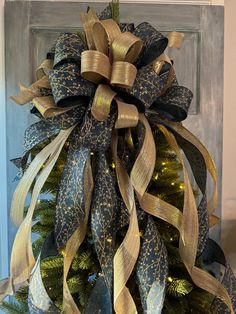 a christmas tree decorated with gold and blue ribbons on top of a wooden door frame