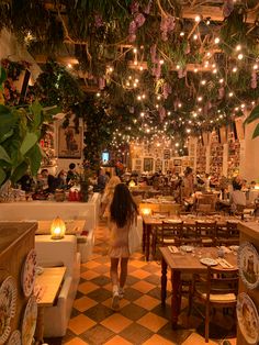 a woman walking through a restaurant filled with tables and chairs