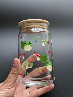 a hand holding a glass with green and red designs on it