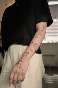 a person with a tattoo on their left arm and the other hand behind her back