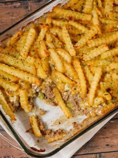 a casserole dish filled with french fries covered in cheese and meat toppings