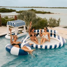 three women sitting on inflatable rafts at the edge of a pool