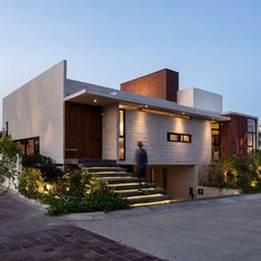 a modern house with stairs leading up to it's front door and side entrance