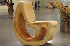 a wooden chair sitting on top of a cement floor next to vases and sculptures