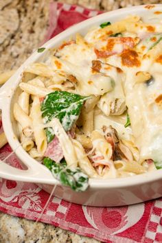 a pasta dish with chicken, spinach and cheese in a white casserole dish