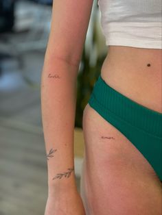 a woman's lower body with tattoos on her left arm and the word love written in cursive writing