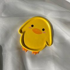 a yellow bird shaped object sitting on top of a white sheet