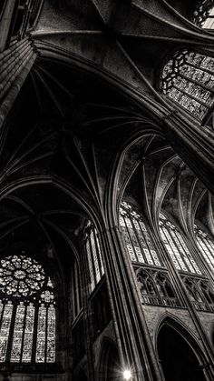 black and white photograph of the inside of a cathedral with stained glass windows in it