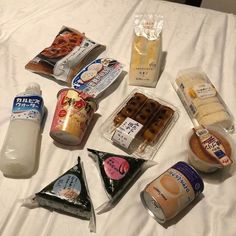 an assortment of food items laid out on top of a white bed spread with milk, yogurt, eggs, and other condiments