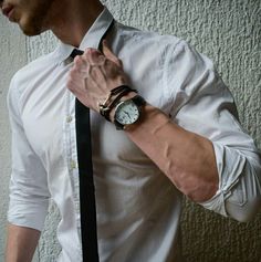 a man wearing a white shirt and black tie with a watch on his left wrist