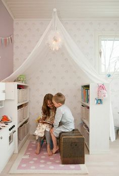 two children are sitting on a bench in a room with pink walls and flooring