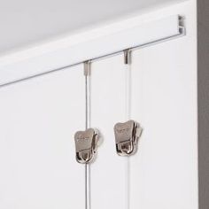 two metal latches are attached to the side of a white cabinet with glass doors