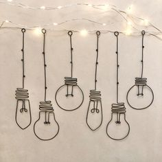 five light bulbs hanging from strings with string lights on the wall in the back ground