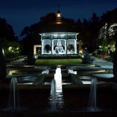 a gazebo lit up at night with water running through it