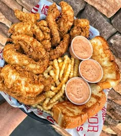 a basket filled with fried chicken and french fries next to dipping sauces on top of it