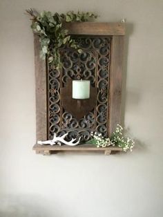 a wall mounted candle holder with flowers and antlers on it next to a mirror