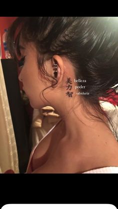 a woman wearing ear piercings with chinese writing on her left side behind her ear