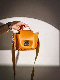 A mini handbag is always a versatile staple, but when it's crafted from premium natural leather in a bold orange hue with silver hardware, it reaches a whole new level of sophistication. This handcrafted, one-of-a-kind piece combines timeless style with modern functionality. Though compact, this bag is designed to hold all your essentials--phone, lipstick, keys, and other small items--making it both practical and chic. The high-quality leather and meticulous handcrafting process ensure a luxury Handbag Care, Orange Handbag, Leather Handbags Handmade, Mini Handbag, Brown Handbag, Leather Conditioner, Mini Handbags, Orange Leather, Small Crossbody Bag