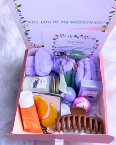 a pink box filled with lots of different items on top of a white fur rug