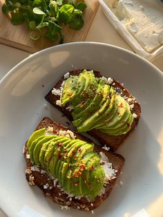 two pieces of bread with avocado on top and sprinkled cheese on the side