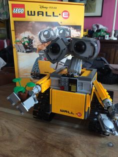 a lego wall - e robot sitting on top of a table next to a box