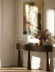 a painting hangs on the wall behind a console table