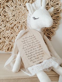 a stuffed giraffe sitting on top of a wooden shelf next to a plaque