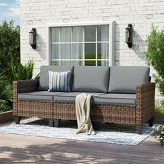 a couch sitting on top of a wooden floor next to a white brick building with windows