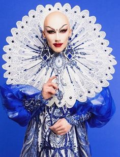 a woman in a blue and white costume with an elaborate head piece on her face