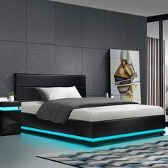 a modern bedroom with black walls and white furniture, including a bed that has blue lights on the headboard