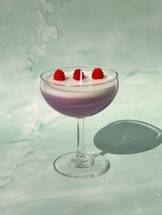 a drink in a glass with raspberries on the rim and garnish