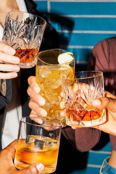 several people holding up glasses filled with different types of drinks and beverages in their hands