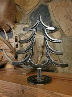 a metal christmas tree with antlers on it's sides sitting in front of a stone wall