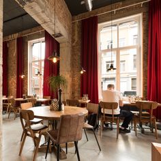 an empty restaurant with tables and chairs in front of a brick wall that has windows